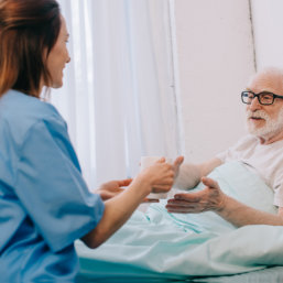 caregiver giving a mug of water on senior